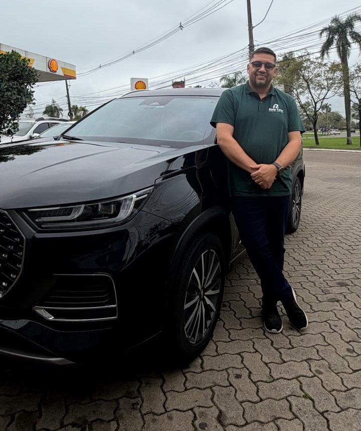 Rafael, motorista-guia do Rafa Tour, encostado no Chery Tiggo 8 Pro preto, o carro do Rafa Tour