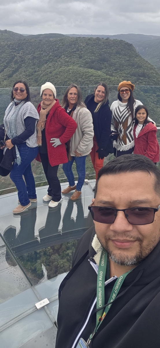 Grupo de mulheres com o Rafa em mirante de vidro com vista para vale na Serra Gaúcha