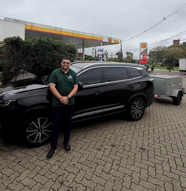 Rafael ao lado do Chery Tiggo 8 Pro do Rafa Tour, com o reboque exclusivo para malas engatado